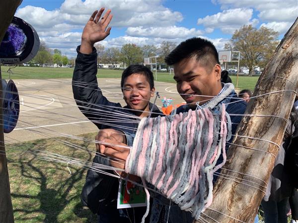 Students engaging in outdoor project with yarn